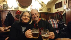 Clientes do Praga Boêmia, Angelina e Ricardo, no beer tour, brindando com um caneco de 500 ml de cerveja pilsen em um pub