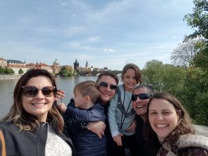 Família com crianças posando para a foto com a Ponte Carlos de Praga ao fundo