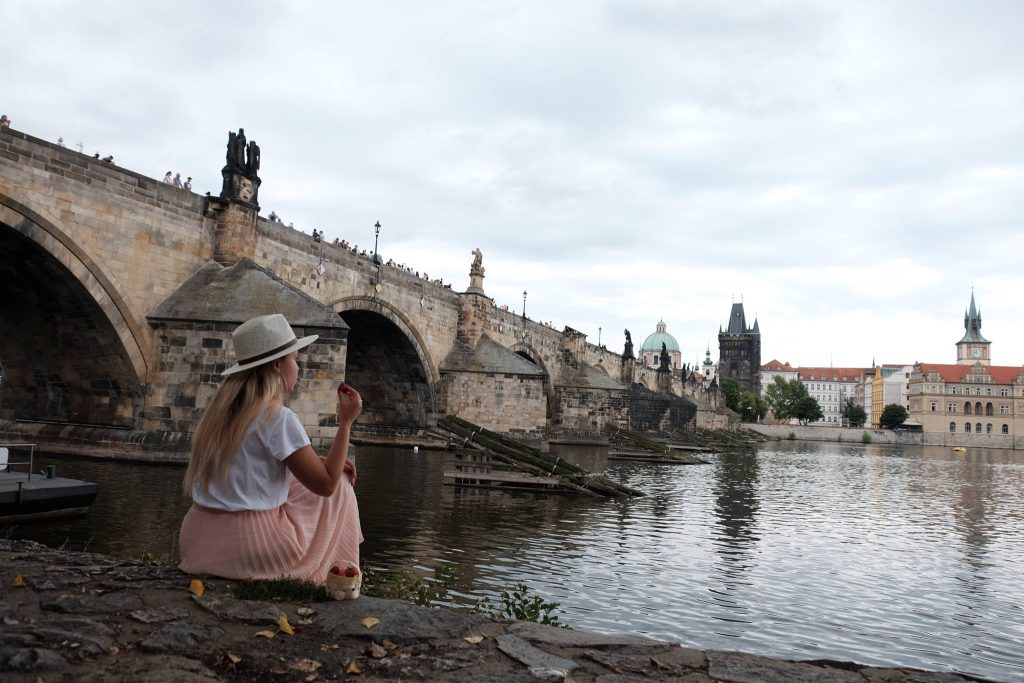 Mulher jovem vestida com roupas de verão na beira do rio Vltava em Praga