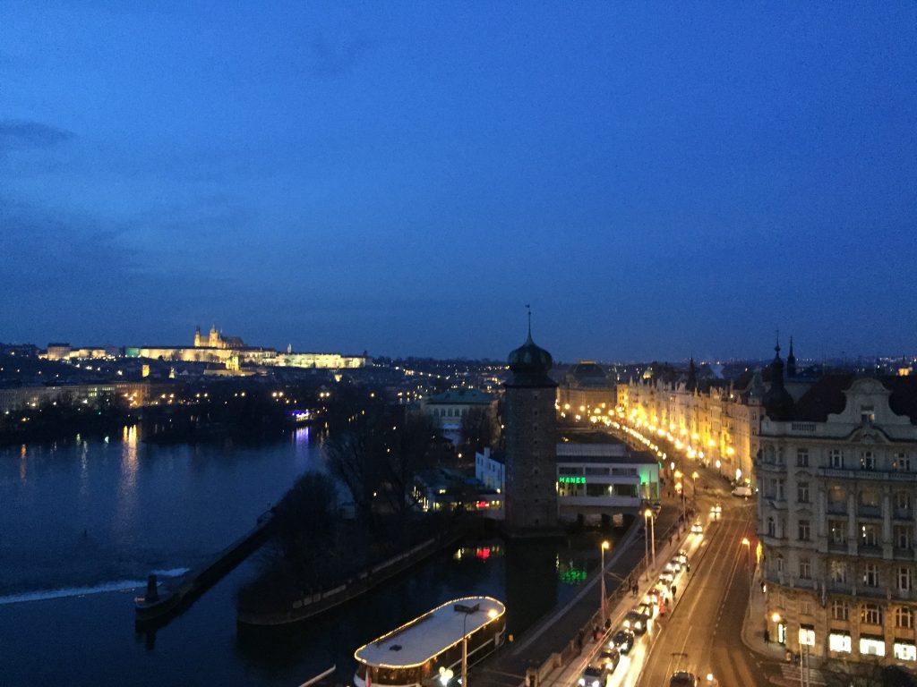 Panorama da cidade de Praga com o castelo no horizonte e os prédios à beira do rio Vltava 