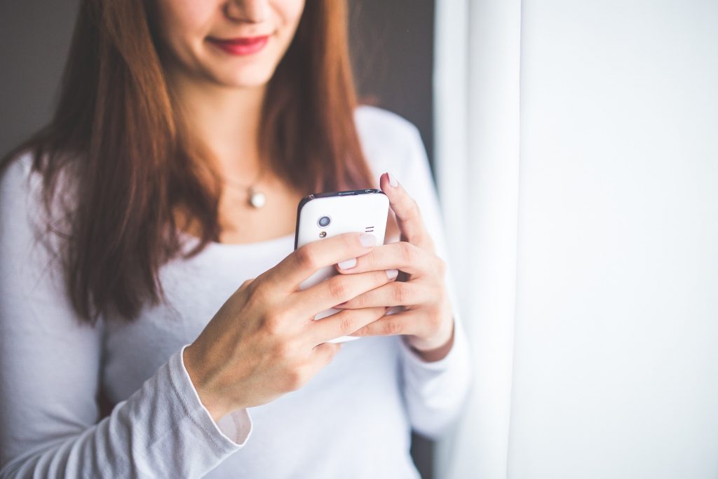 Mulher jovem olhando para a tela do celular e respondendo mensagens