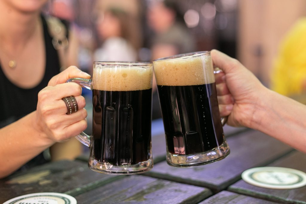Duas canecas de cerveja escura brindando
