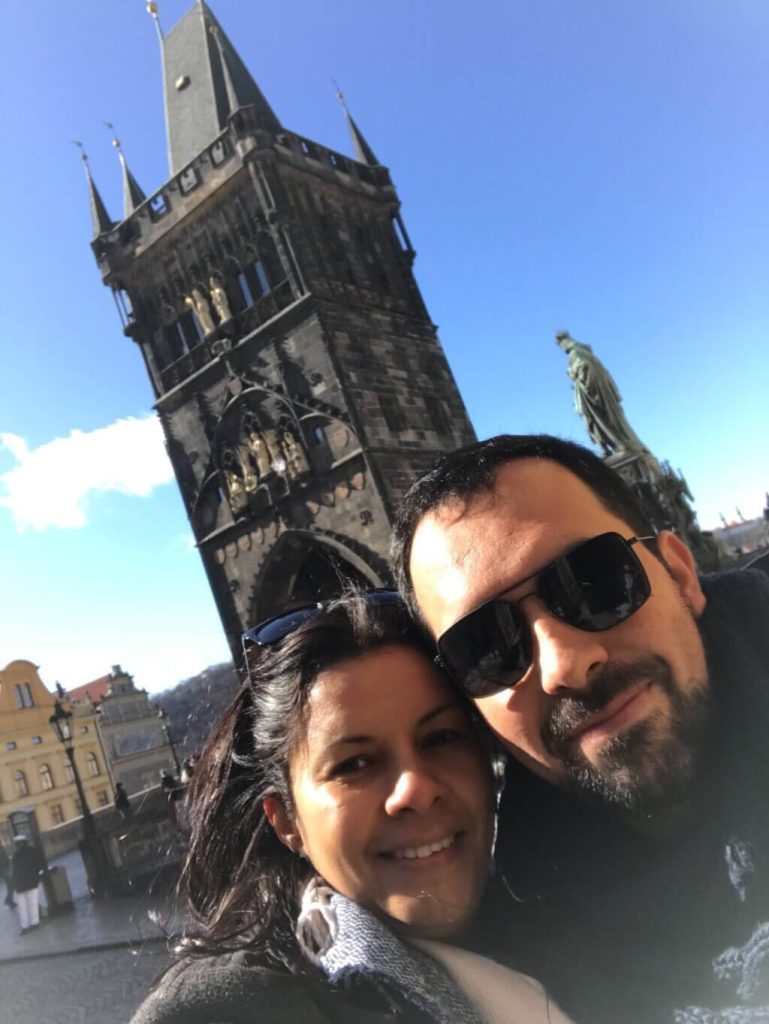 Cristiane e marido em passeio pela cidade de Praga. Fotografaram com o fundo para a torre da Cidade Velha
