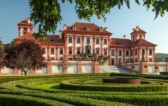 Fachada barroca de um palacio majestoso com um jardim ornamentado à frente do palacio em Praga